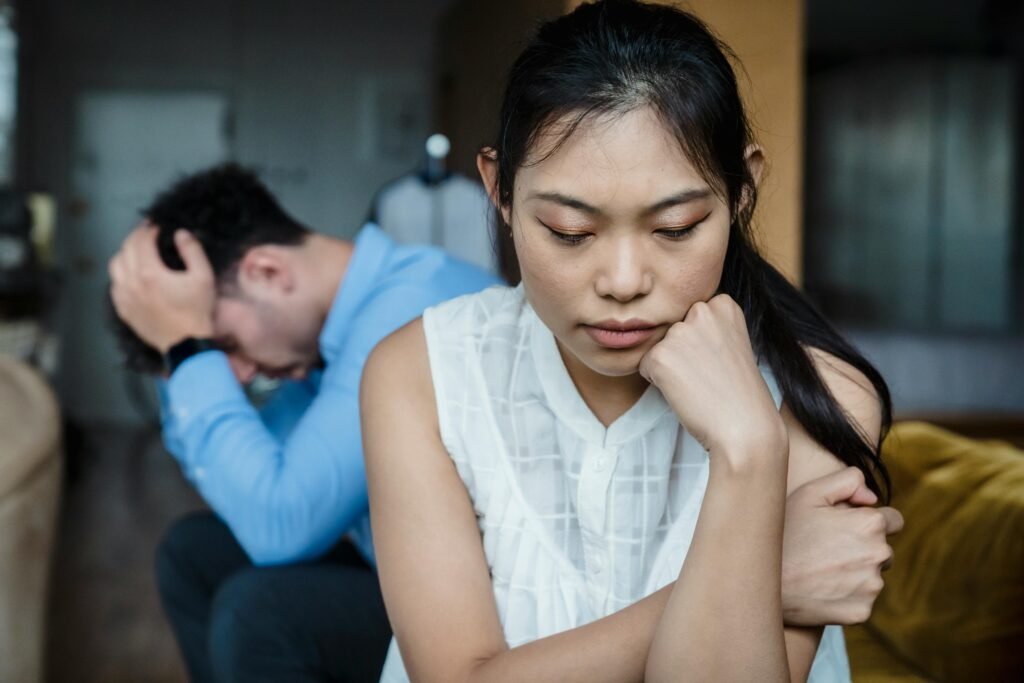 A couple experiencing relationship tension sitting silently on a sofa.